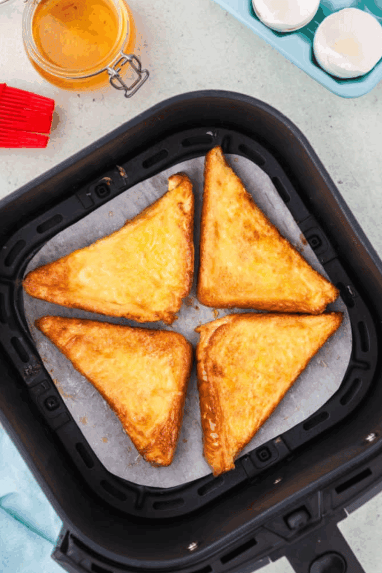 Golden, crispy air fryer honey toast drizzled with honey and served on a plate.