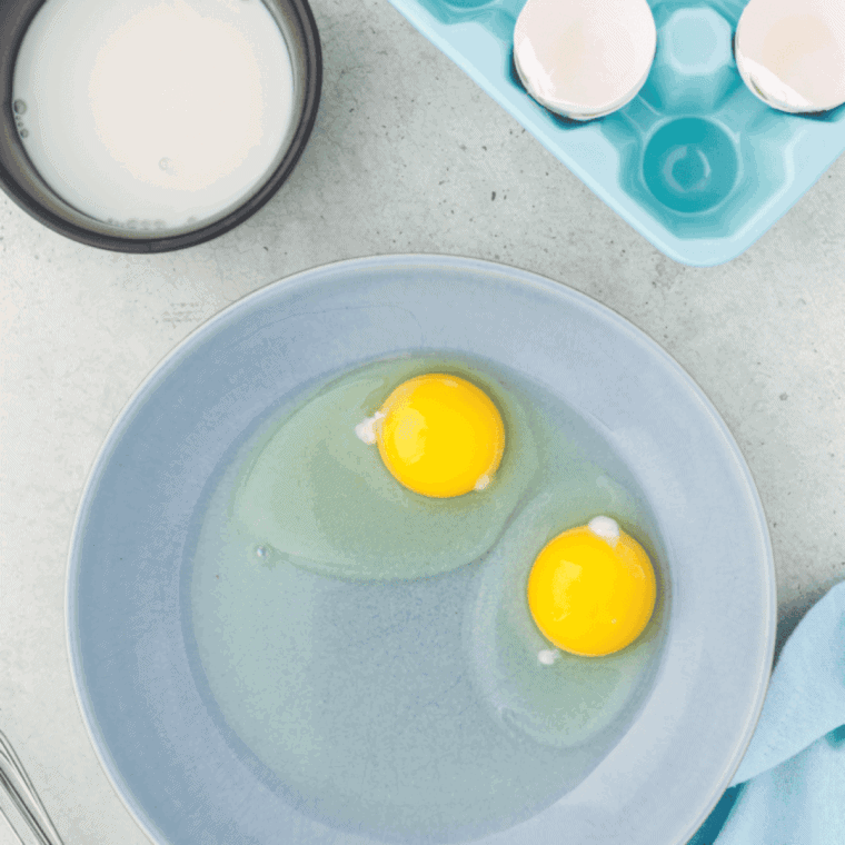 Whisking eggs and milk together in a small bowl while the air fryer preheats.