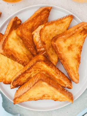 Crispy golden air fryer honey toast topped with melted butter and drizzled honey on a plate.