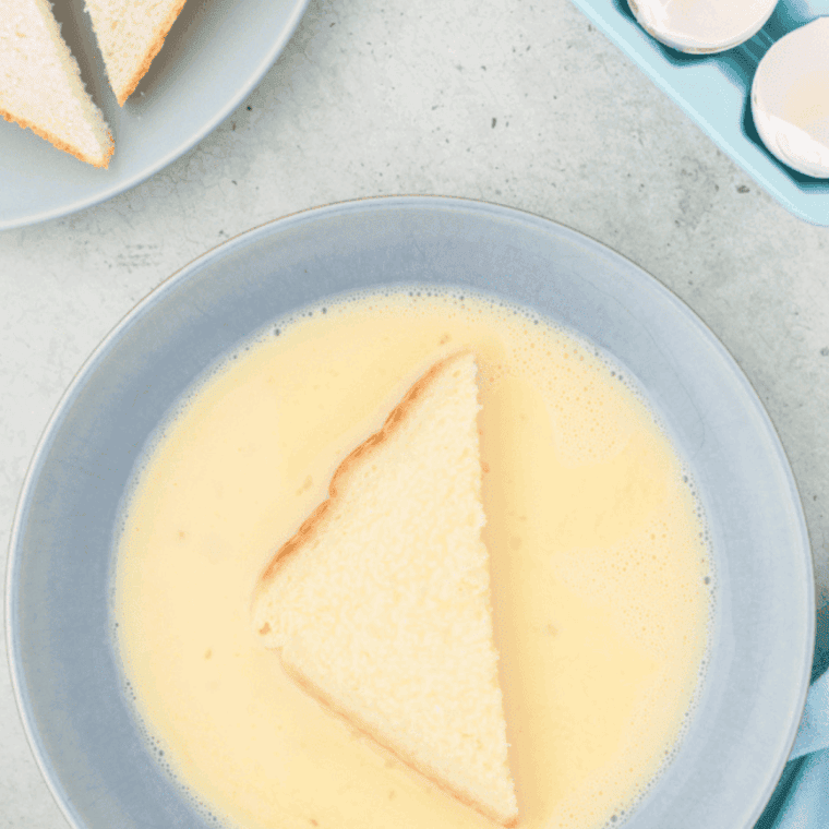 Slicing bread diagonally and dipping each piece into the egg and milk mixture, fully coating both sides.