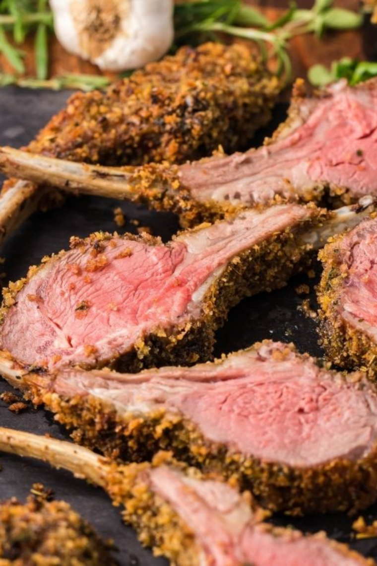 Juicy herb-crusted lamb cutlets plated on a black dish