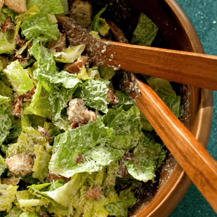 Bowl of copycat Outback Caesar dressing with romaine and shaved Parmesan