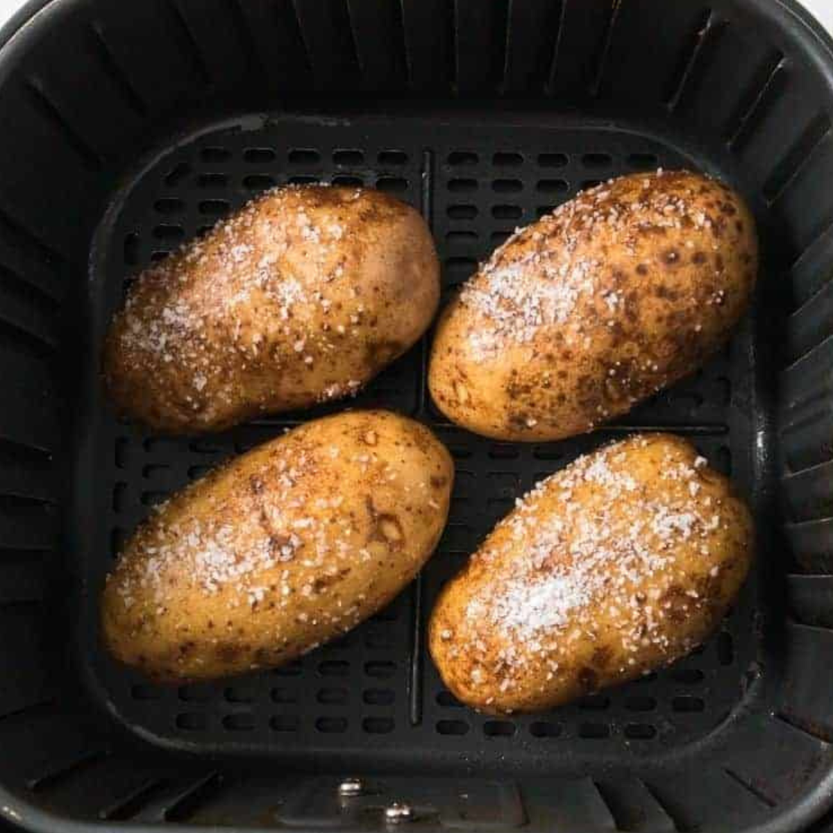 Frozen jacket potato cooking in an air fryer basket.