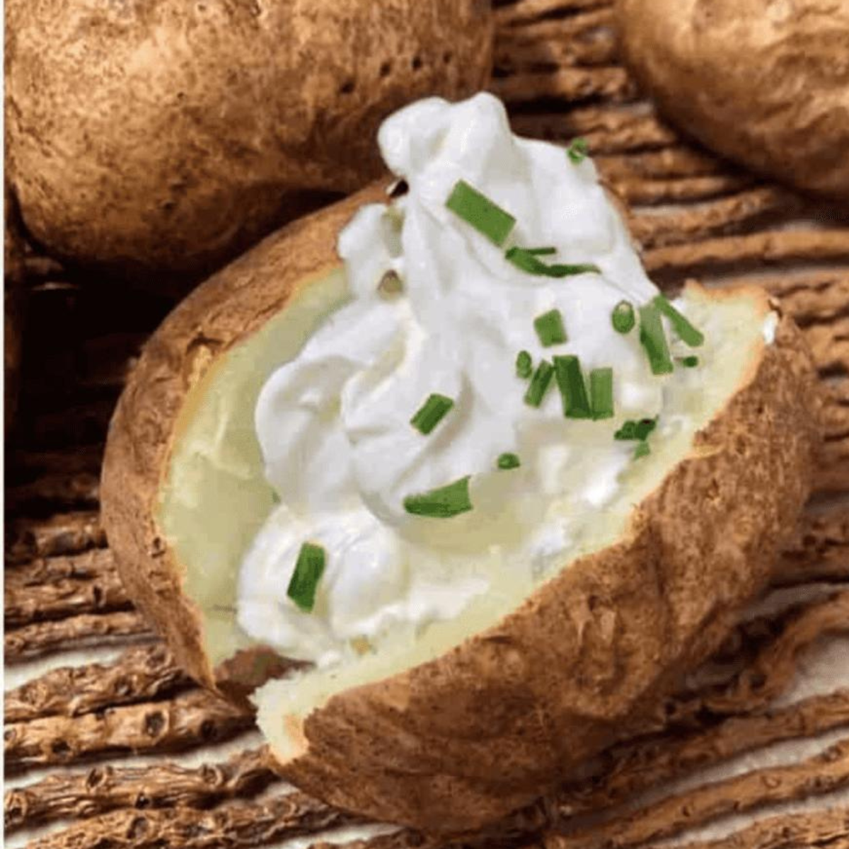 Cooked jacket potato topped with sour cream on a plate."