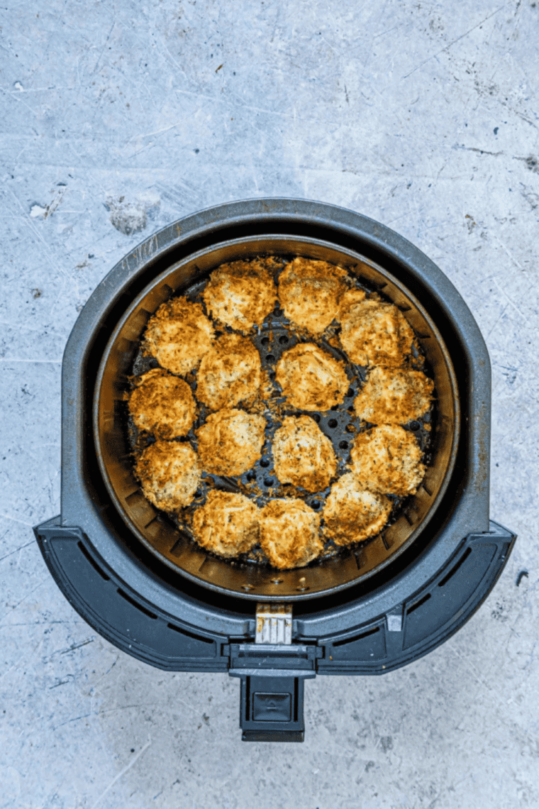 Breaded tortellini arranged in a single layer in the air fryer basket before cooking