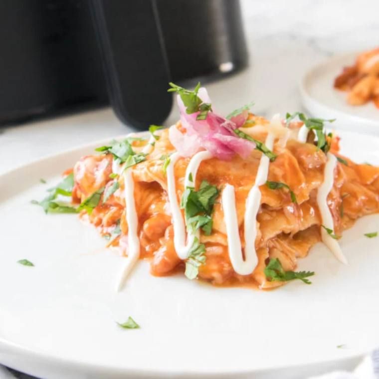 Garnished reheated enchiladas served on a colorful plate.