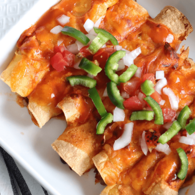 Freshly reheated enchiladas topped with cheese and cilantro on a serving plate.