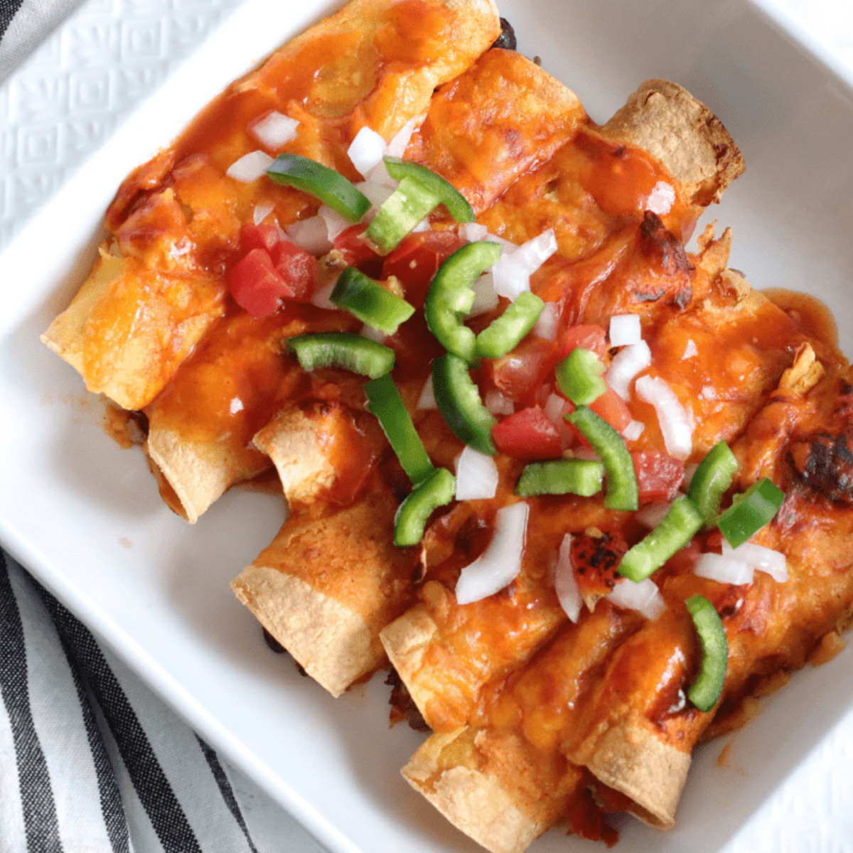 Serving reheated enchiladas straight from the air fryer on a plate.