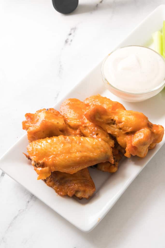 overhead of rectangle platter with buffalo wings, ranch dip, and celery