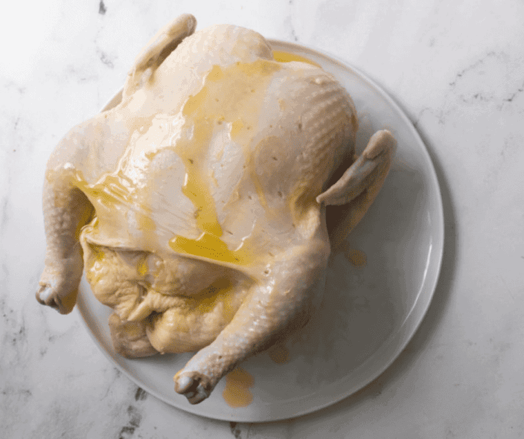 uncooked whole chicken drizzled with oil
