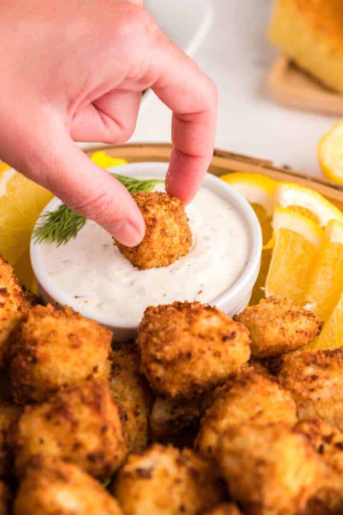 dipping crispy fish nuggets in creamy sauce