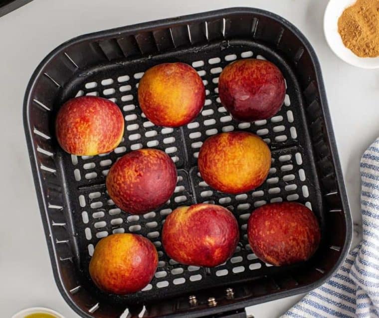 top view of peaches in air fryer basket. 