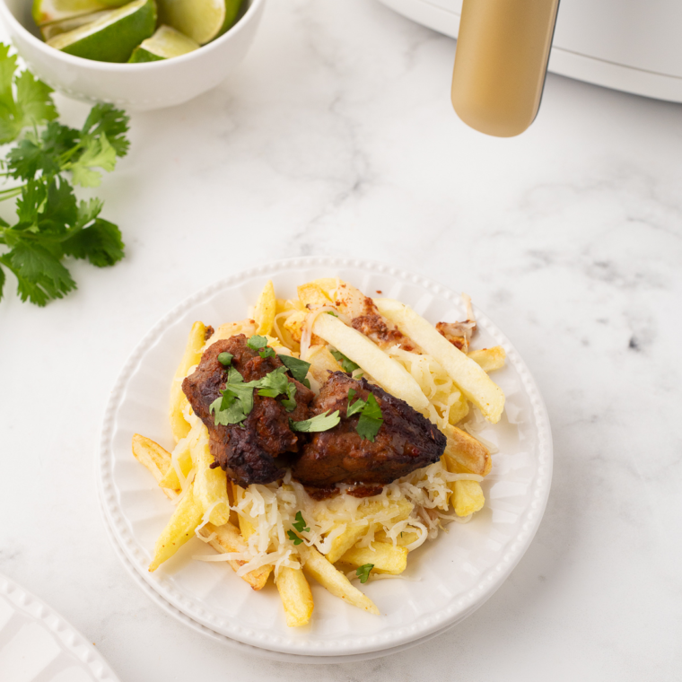 Crispy Air Fryer Birria Fries topped with juicy beef, melted cheese, and a drizzle of consommé.