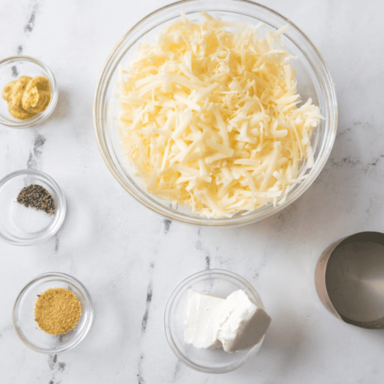 Ingredients needed for Air Fryer Creamy White Cheddar Beer Cheese Sauce on kitchen table.