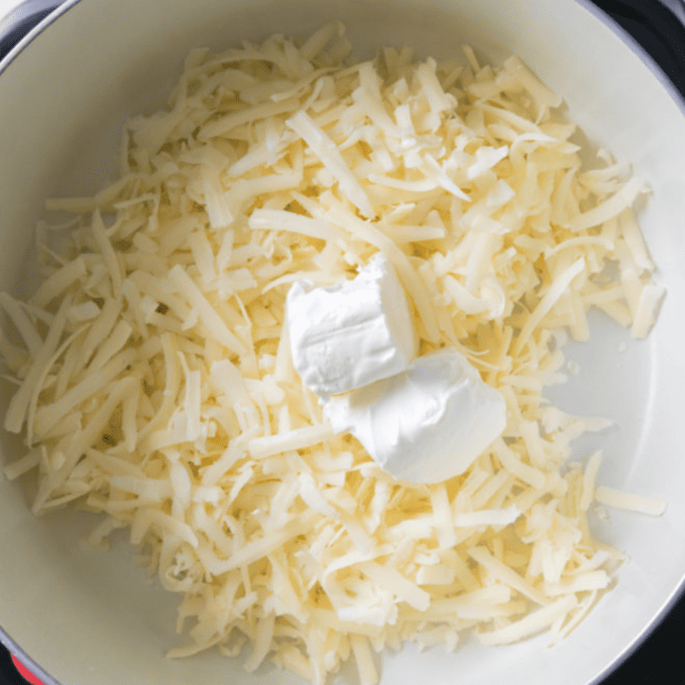 Melting white cheddar and cream cheese in a saucepan with seasoning and beer for a smooth, creamy sauce.