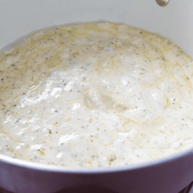 Cheddar and cream cheese melting in a saucepan with seasoning and beer for a rich, creamy sauce.