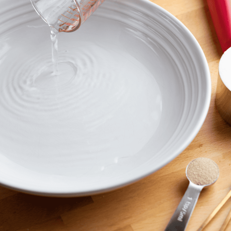 Activating yeast with warm water and mixing dough ingredients for Turkish balloon bread, including flour, salt, and olive oil.