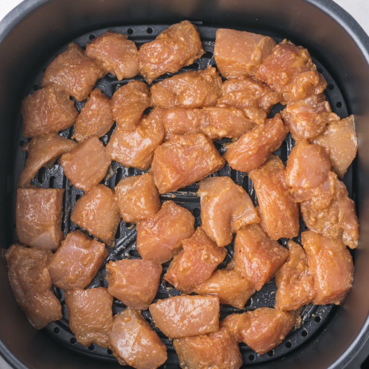 Preheating the air fryer to 370°F, cooking marinated chicken for 3 minutes per side until golden brown and reaching 165°F.