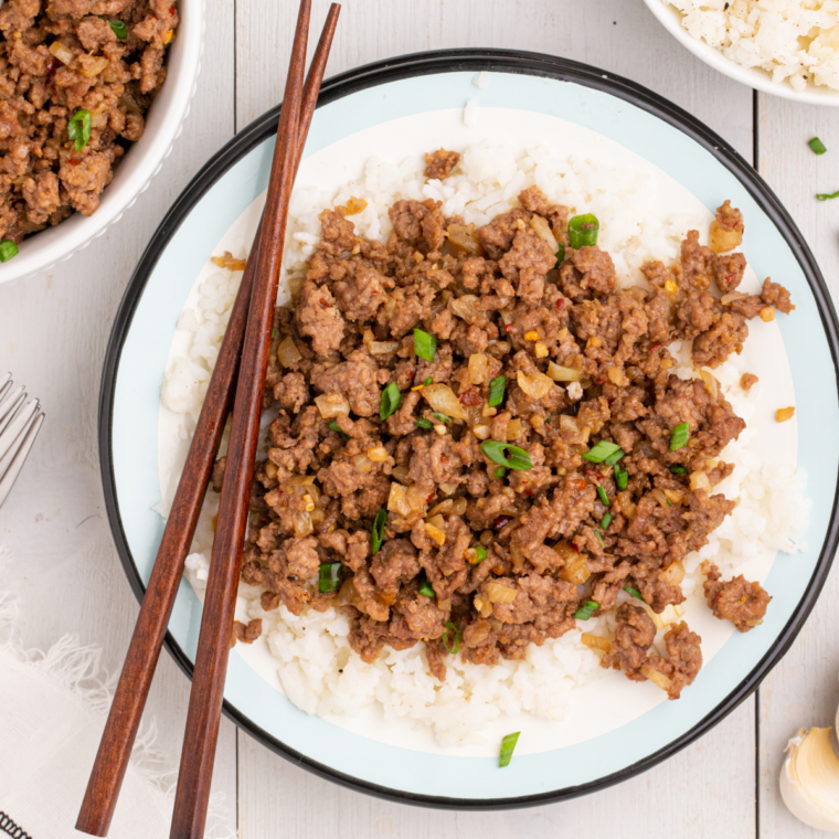 A bowl of Air Fryer Korean Ground Beef served over steamed white rice, garnished with green onions and sesame seeds for a colorful, flavorful presentation.