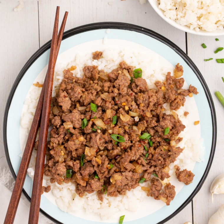 A hearty serving of Air Fryer Korean Ground Beef and Rice Bowls, garnished with green onions and sesame seeds, served with fluffy white rice.