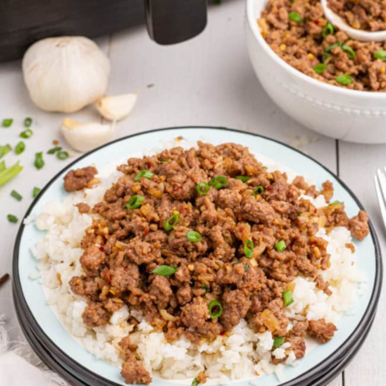 A delicious Air Fryer Korean Ground Beef and Rice Bowl garnished with green onions and sesame seeds, served with fluffy white rice.