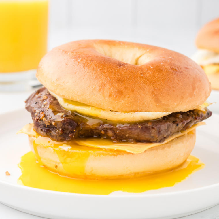 Close-up image of an Air Fryer McDonald’s-style Steak, Egg, and Cheese Bagel with melted cheese, tender steak, and scrambled eggs on a toasted bagel, showcasing a golden crispy texture.