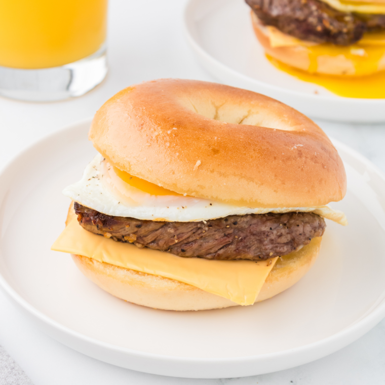 "Close-up image of a delicious homemade Steak, Egg, and Cheese Bagel with melted cheese, scrambled eggs, and juicy steak on a toasted bagel."
