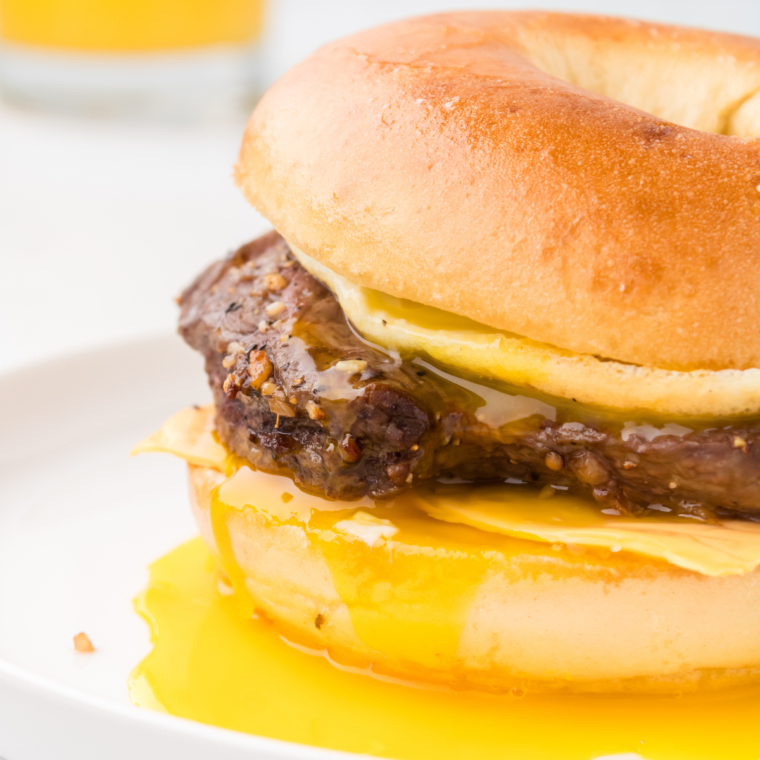 "Close-up image of a delicious homemade Steak, Egg, and Cheese Bagel with melted cheese, scrambled eggs, and juicy steak on a toasted bagel."