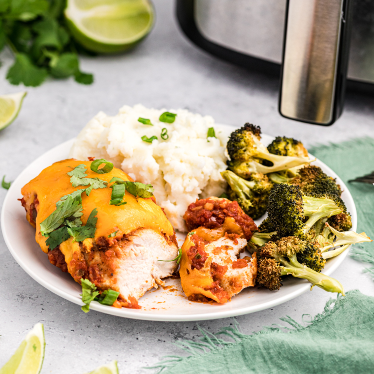 A plate of Air Fryer Salsa Chicken topped with fresh cilantro and served with lime wedges, perfect for tacos or burrito bowls.