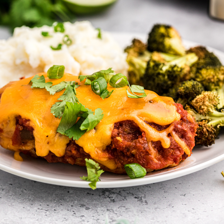 "Air fryer salsa chicken topped with fresh cilantro and served with lime wedges, presented on a white plate for a vibrant and healthy meal option."