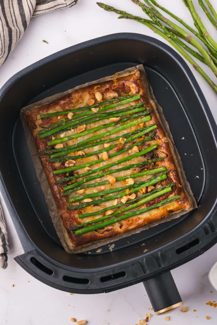 Golden air fryer asparagus tart with cheese, saut&eacute;ed onions, and fresh herbs.