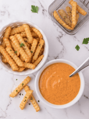 Copycat McDonald's buffalo sauce in a bowl with a chicken nugget being dipped