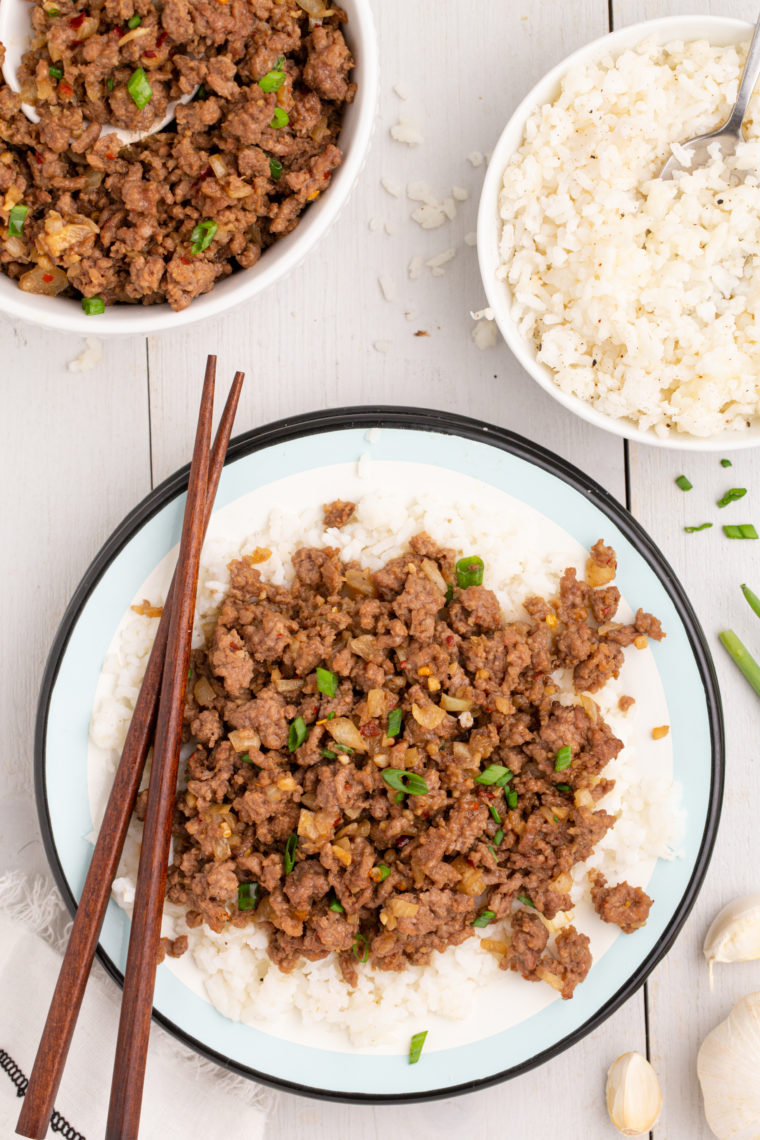 A bowl of Air Fryer Korean Ground Beef served over steamed white rice, garnished with green onions and sesame seeds for a colorful, flavorful presentation.