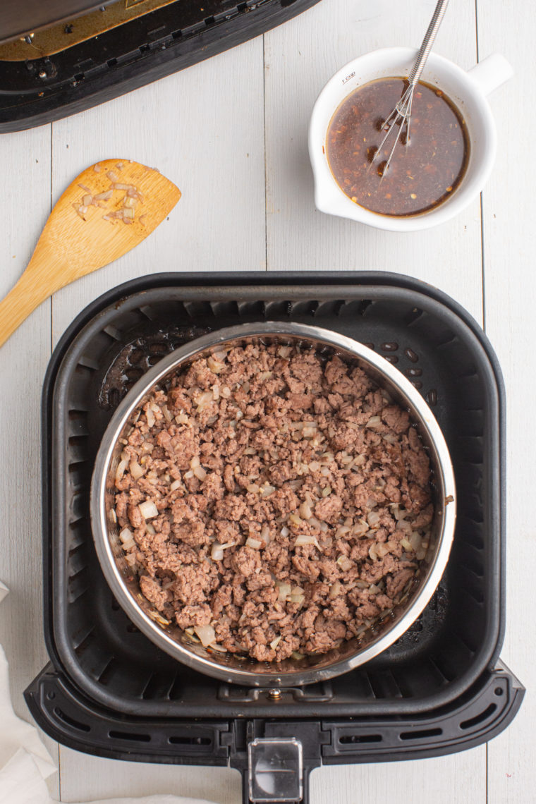 Cooked season ground beef in air fryer basket.