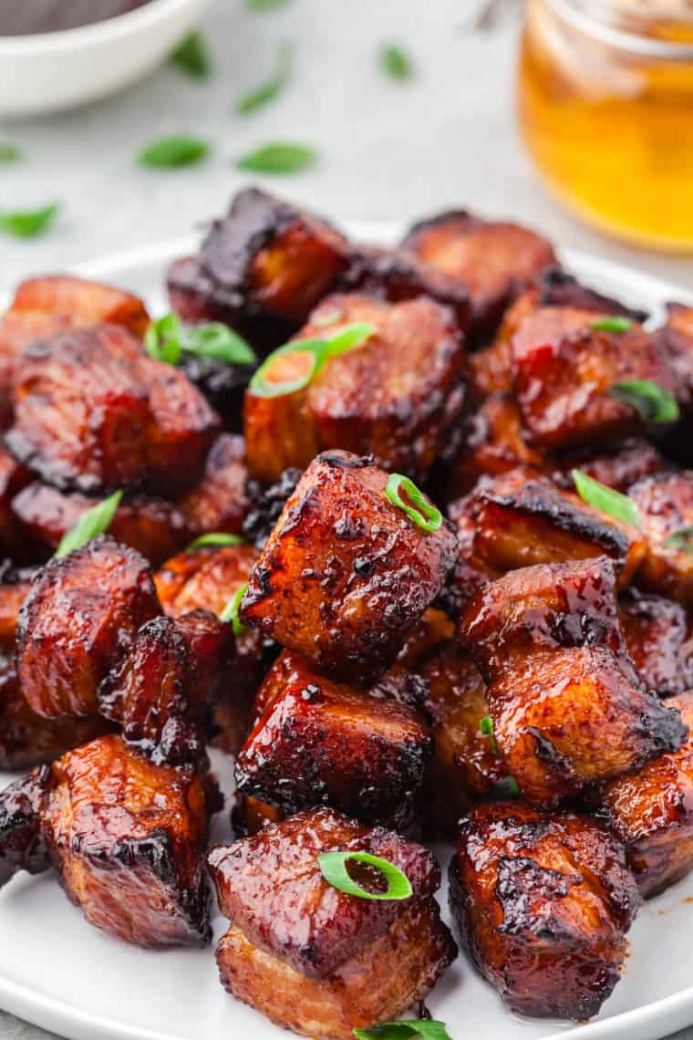 Sticky honey pork belly bites piled in a small cast iron skillet with toothpicks for a party appetizer