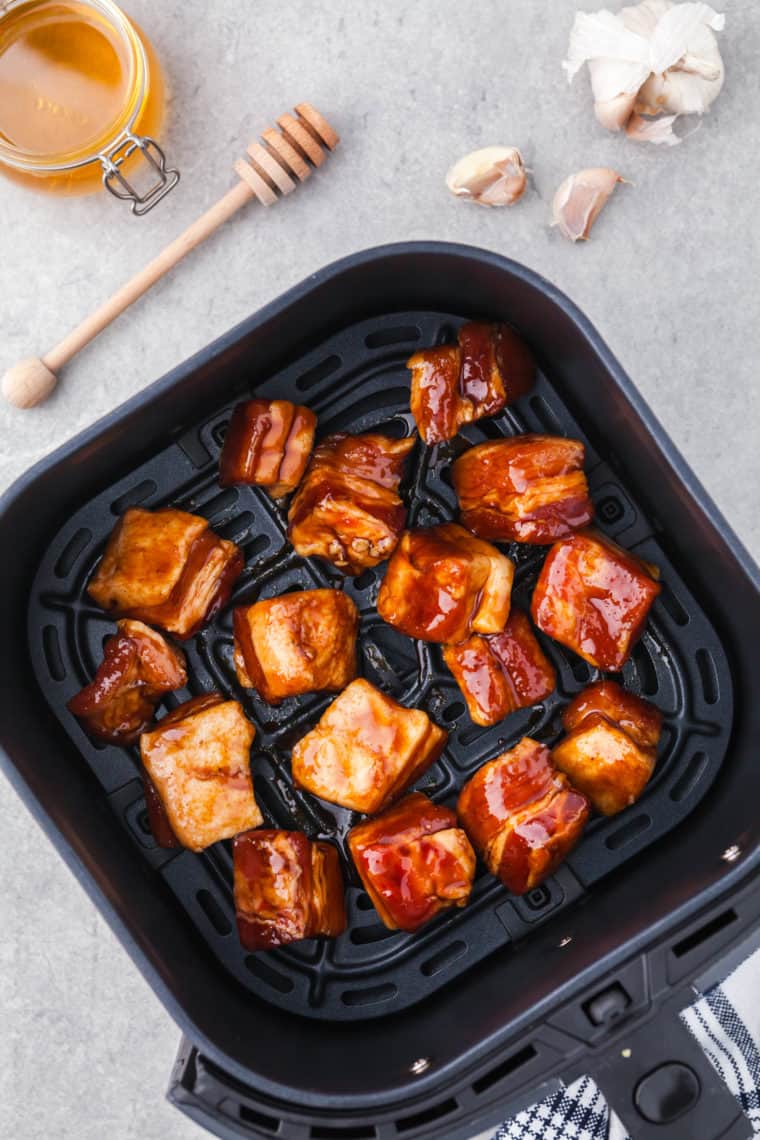 Seasoned pork belly cubes arranged in a single layer inside an air fryer basket