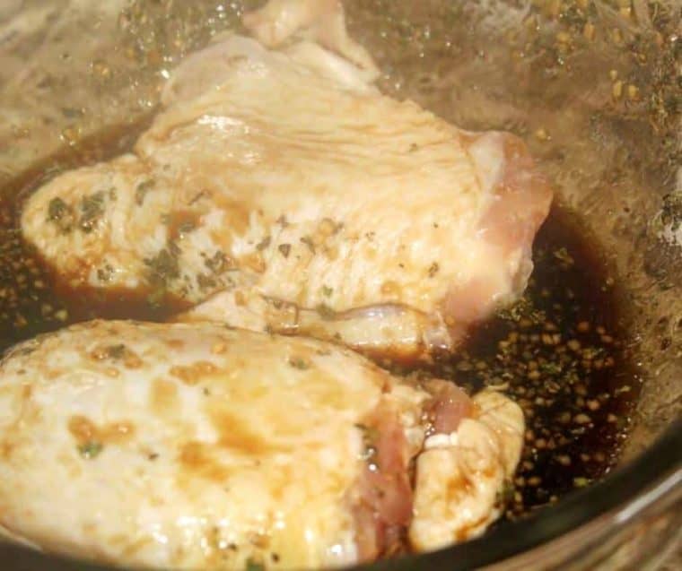 Chicken thighs in a bowl marinating in a brown sugar glaze for chicken. 