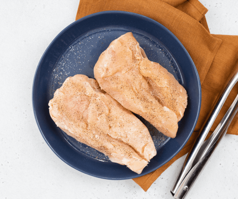 seasoned chicken breasts in shallow blue bowl