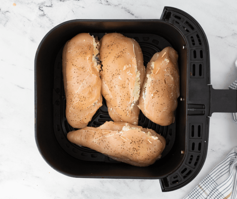 seasoned chicken breasts stuffed with cheese filling in air fryer basket
