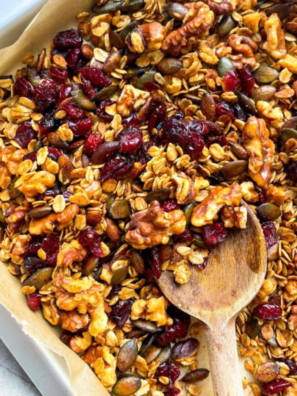 Cranberry Granola on a plate with a wooden spoon scooping some cooked air-fried cranberry granola up.