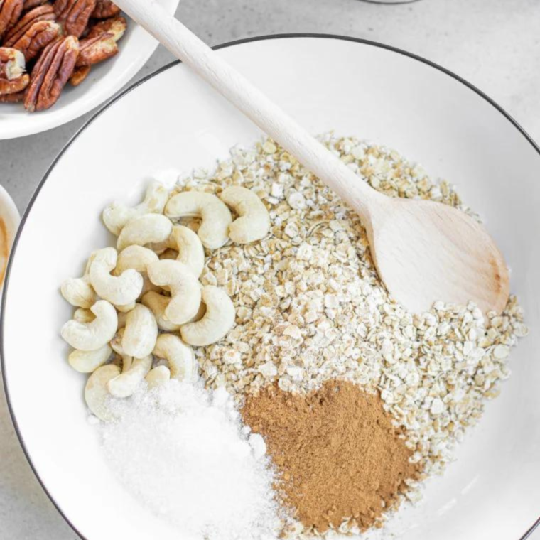 White bowl of ingredients in it, with a wooden spoon mixing them up. 