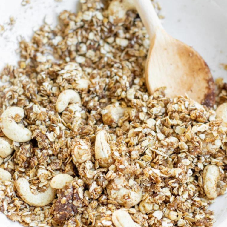 Cranberry Granola ingredients in a white bowl, being mixed.