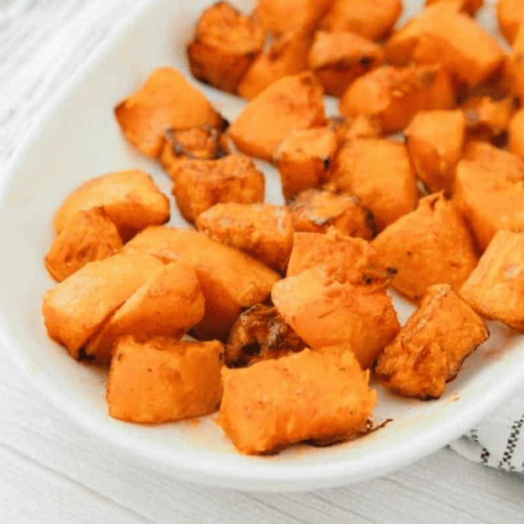 Cooked butternut squash cubes resting in a bowl before serving, edges crisped and browned  