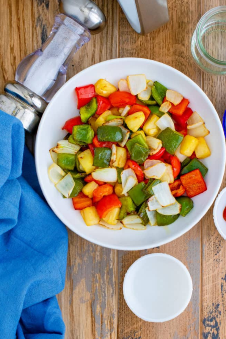 Cooked Air Fryer Peppers and Onions garnished with fresh herbs.