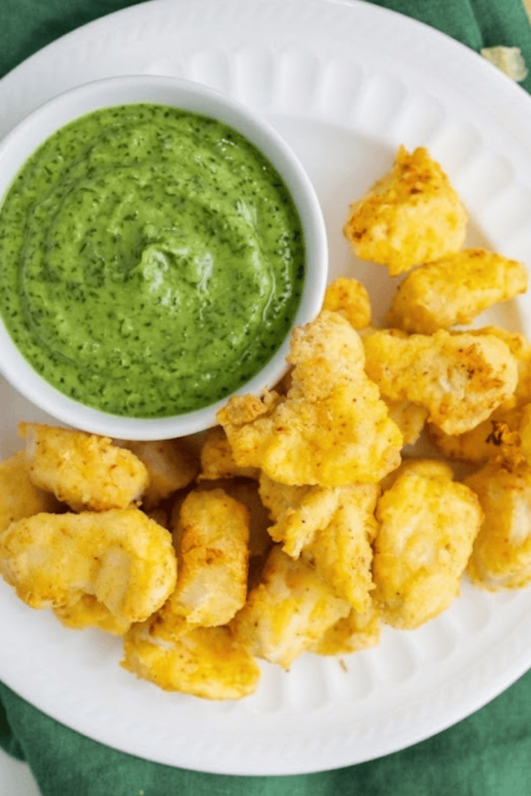creamy avocado lime ranch dressing in bowl with fresh herbs and lime wedges