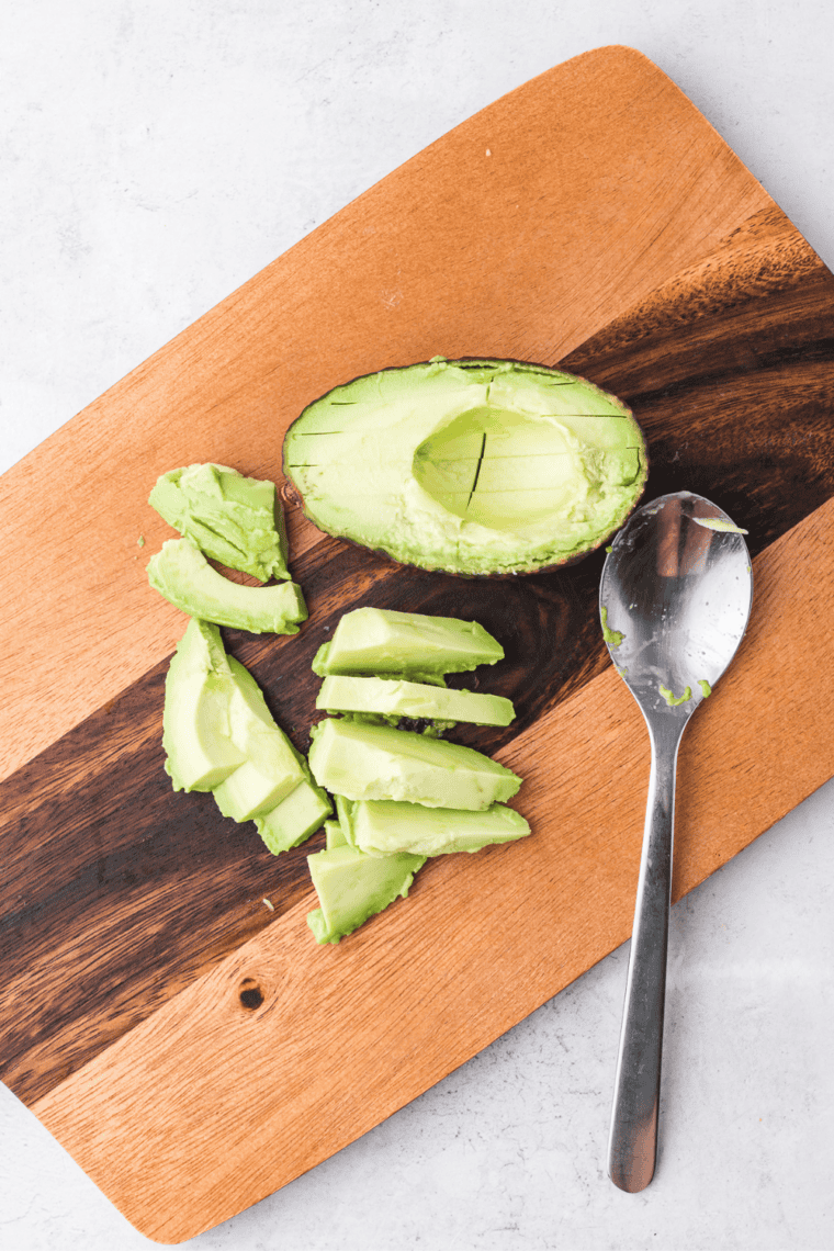 ripe avocado halves being scooped into blender for creamy dressing