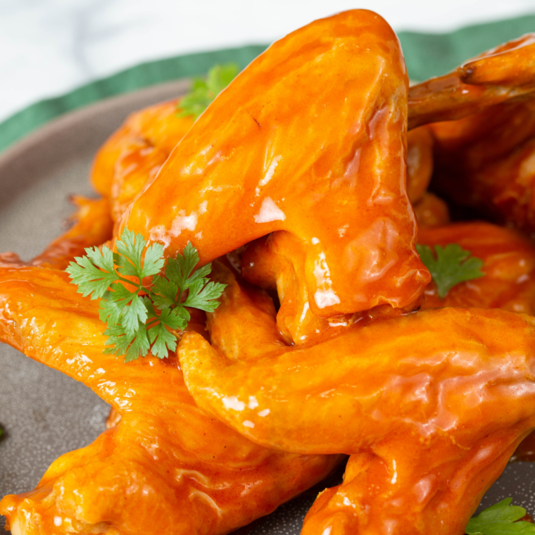 Overhead plate of crispy wings with celery sticks and ranch dressing
