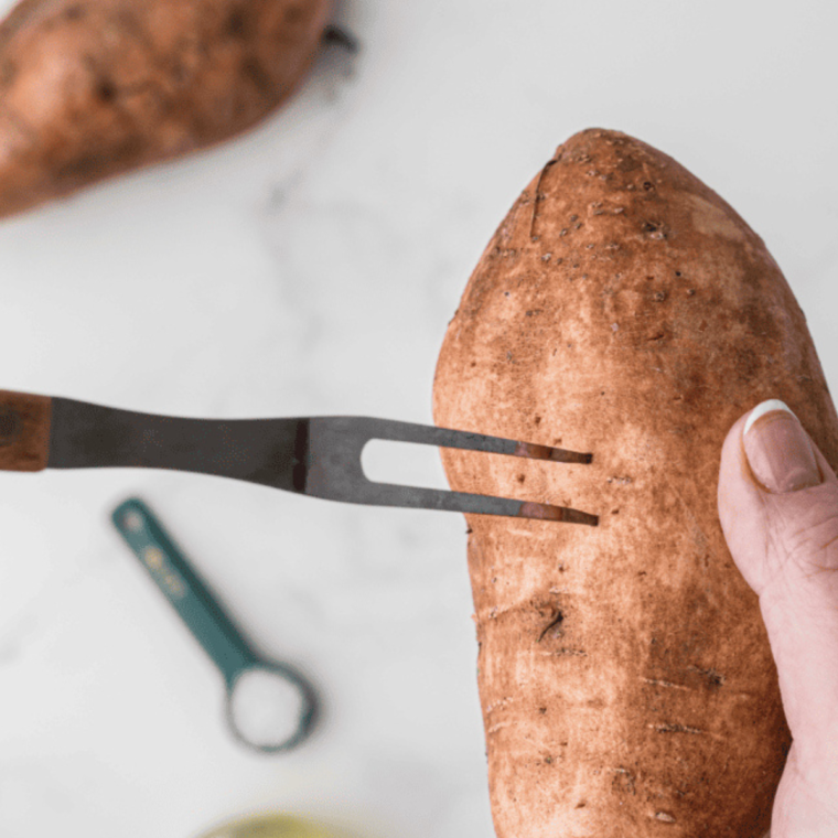 Seasoning sweet potatoes with olive oil, salt, and pepper before baking in the Ninja Foodi.