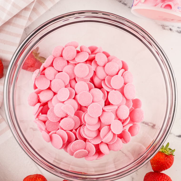 Pink candy melts being melted in a microwave-safe bowl until smooth