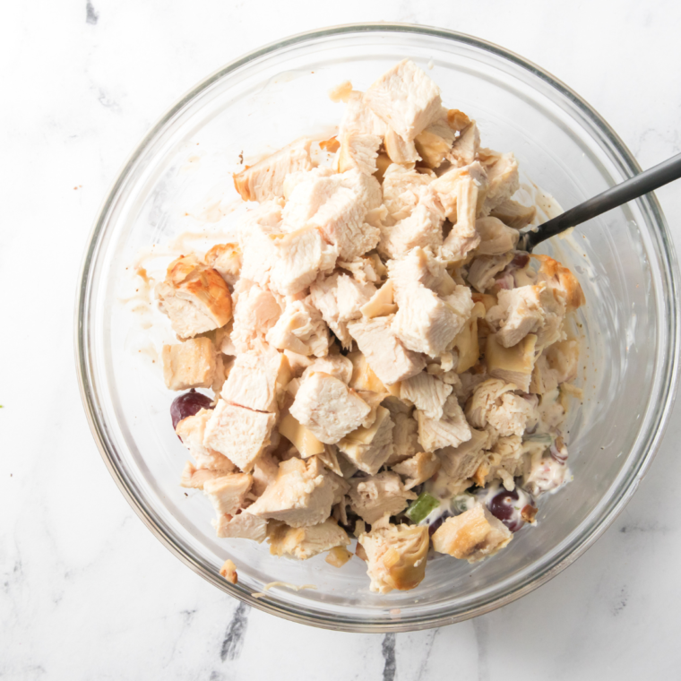 Shredding cooked chicken into a mixing bowl.